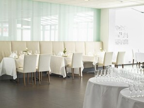 A restaurant with multiple tables set for dining, featuring a modern interior with light-colored walls and a large window allowing natural light. - Park Inn By Radisson Reykjavik Keflavik Airport (Reykjanesbær)