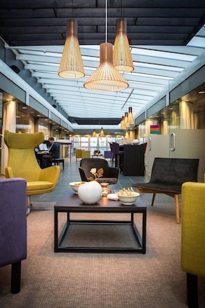 A modern hotel lobby with a central coffee table, seating area, and pendant lighting. - Park Inn By Radisson Reykjavik Keflavik Airport (Reykjanesbær)