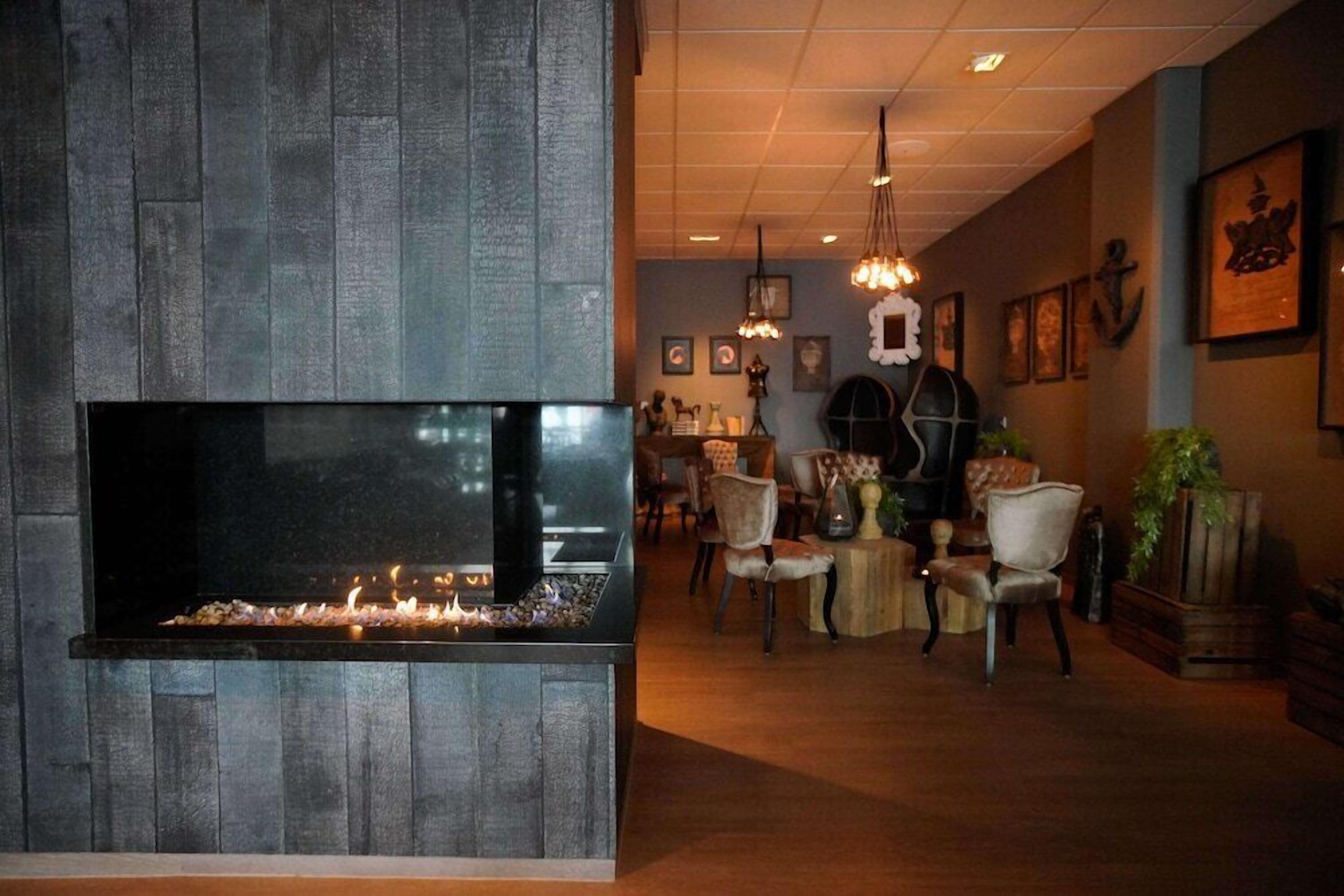 A modern lounge area with a large fireplace, comfortable seating, and decorative wall art.