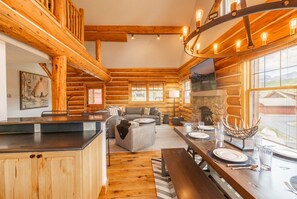 A log cabin interior with a kitchen, dining area, and living space. - Platinum Big Sky Log Cabin | Ski-In/Out, Hot Tub, 2 King Suites & Arcade (Big Sky)