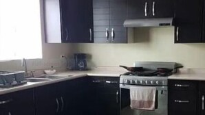 A kitchen with dark cabinets, a stove, and a sink.