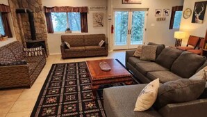 Un salon chaleureux avec une cheminée en pierre, deux canapés, un tapis à motifs et une table basse en bois.
