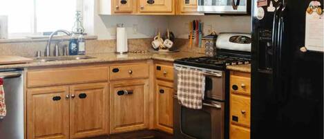 A kitchen with wooden cabinets, a stove, a refrigerator, and a dining table with a vase of flowers.