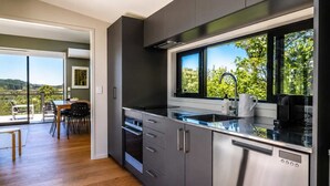 Een moderne keuken met een groot raam, roestvrijstalen apparatuur en een eetgedeelte met uitzicht.