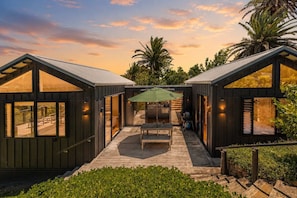 A modern cabin with a wooden deck, a dining area, and a large umbrella.