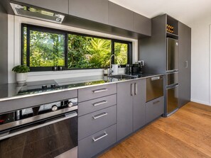 A modern kitchen with a large window, built-in appliances, and a wooden floor.