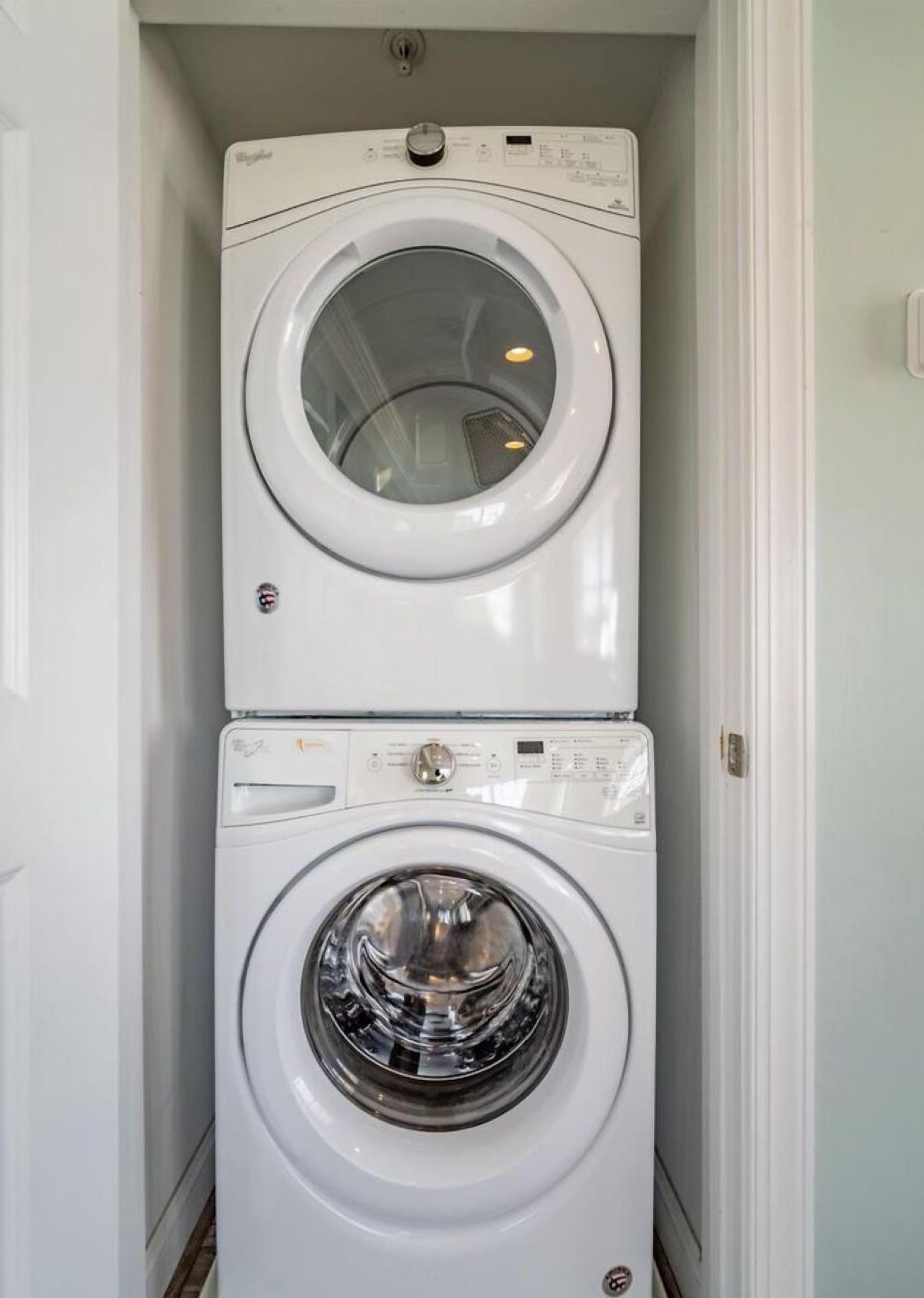 A compact, two-door laundry room with a front-loading washer and dryer stacked vertically.