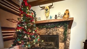 Una sala de estar acogedora con chimenea, un árbol de Navidad y un sofá estampado.