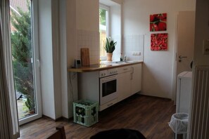 A compact kitchen with a window, a potted plant, and a countertop.