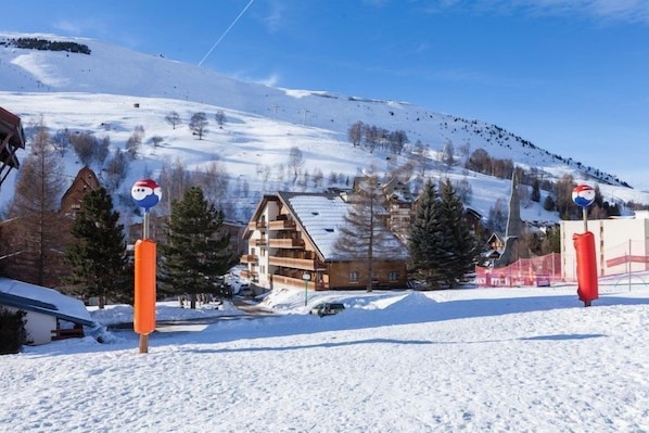 Un paisaje nevado con un chalet de madera y un telesilla al fondo.