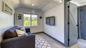 A room with a gray sofa, a patterned rug, a large window, and a door. - ► Modern Tiny House ◄ Big Personality, AC & Views! (Tukwila)