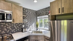 A modern kitchen with wooden cabinets, stainless steel appliances, and a hexagonal tile backsplash. - ► Modern Tiny House ◄ Big Personality, AC & Views! (Tukwila)