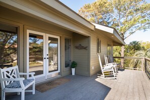 A covered porch with a bench, a rocking chair, and a potted plant. - Perfect Beach House Steps to Ocean! Sleeps 10! Amenity access included! Pet Friendly! (Seabrook Island)