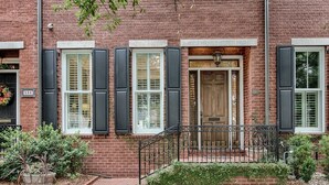 A brick building with three windows, a wooden door, and a small front garden. - Liberty Street Redbrick Town & Carriage House,  Sleeps 8, Private Parking (Savannah)