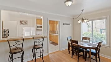 Una cocina con barra, armarios de madera y una mesa de comedor con sillas.