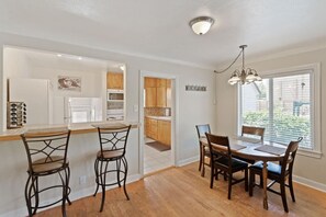 Una cocina con barra, armarios de madera y una mesa de comedor con sillas.