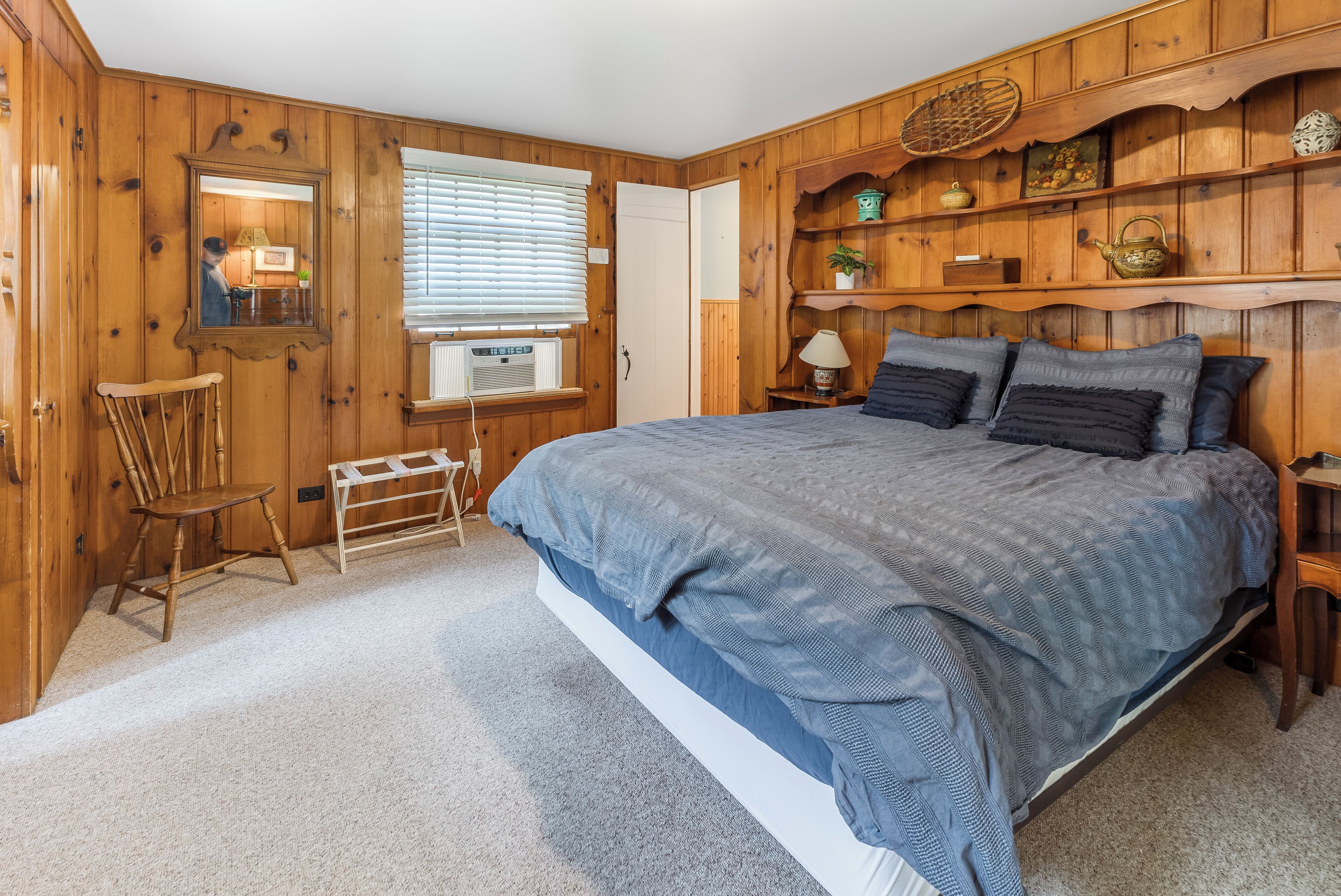 Une chambre avec un grand lit, des murs en bois, un petit bureau et une chaise.