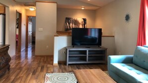 A living room with a flat-screen TV on a wooden stand, a blue sofa, and a patterned rug.