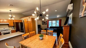 A modern kitchen with wooden cabinets, a central island, and a dining area with wooden chairs and a table.