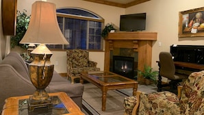 A living room with a fireplace, a television, and a piano.