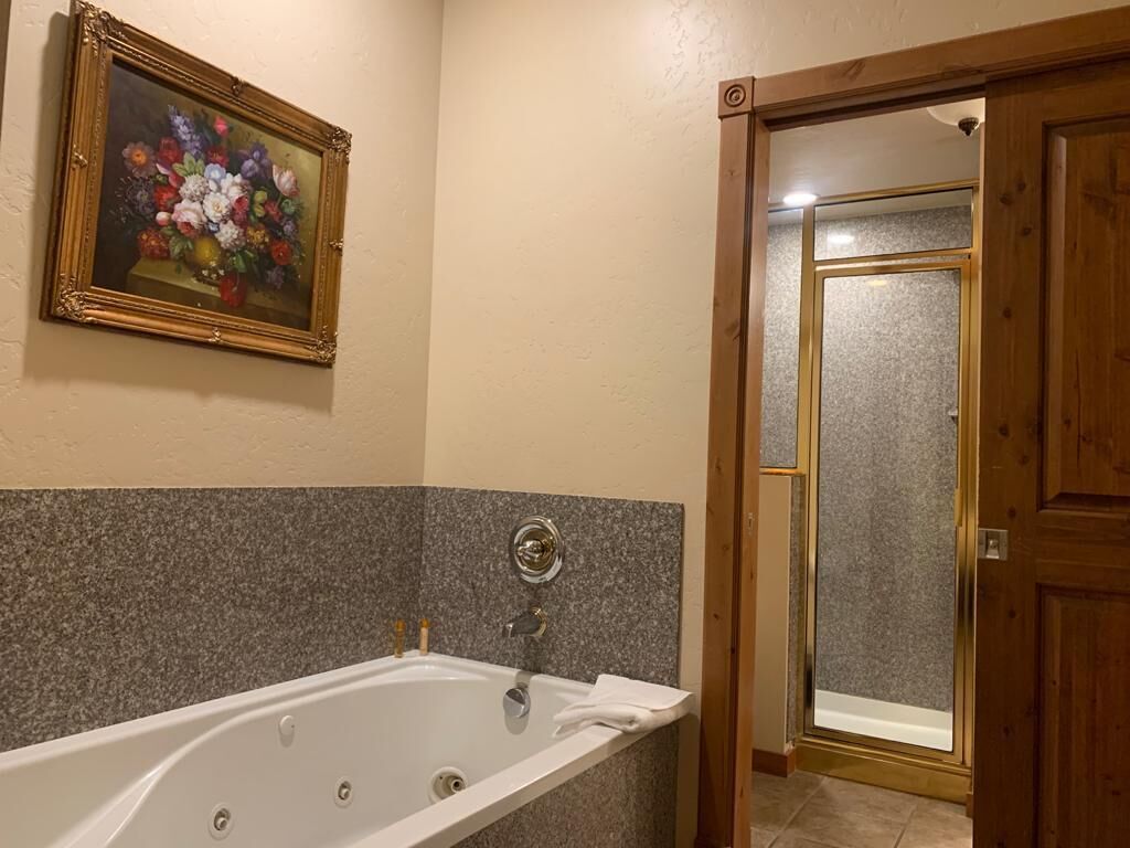 A bathroom with a bathtub, a shower, and a wooden door.