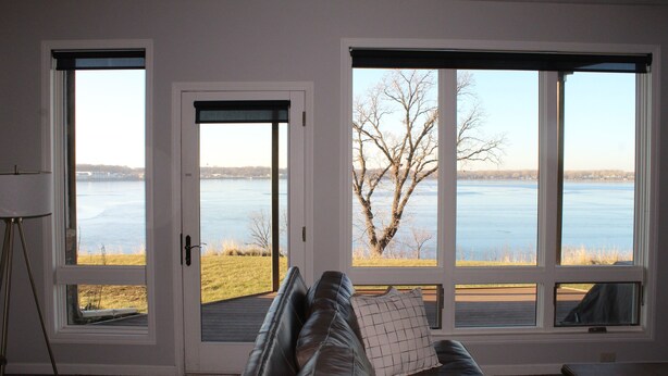 A room with a large window, a leather sofa, and a lamp. - Family-friendly Lakefront East Lake Okoboji Condo- Bridges Bay Resort (Arnolds Park)