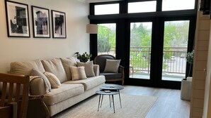 Ein Wohnzimmer mit einer Couch, zwei Sesseln, einem Couchtisch und einem Teppich. An der Wand hängen drei gerahmte Bilder.