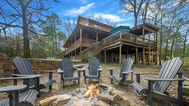 Uma cabana com lareira e cadeiras Adirondack.