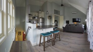 Et rummeligt køkken med en stor ø, barstole og hængende pendellamper.