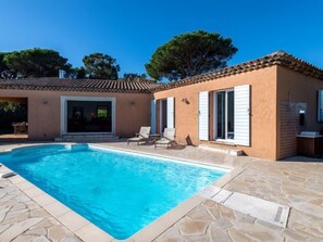 Ein Haus mit Swimmingpool, Sitzgelegenheiten im Freien und einem Ziegeldach.