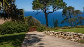 A paved pathway leading to a stone wall with a view of the ocean.