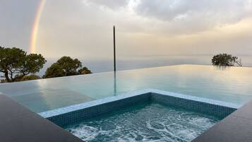 An infinity pool with a view of the sea and a rainbow.