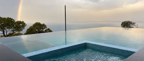 Ein Pool ohne Ende mit Blick auf das Meer und einen Regenbogen.