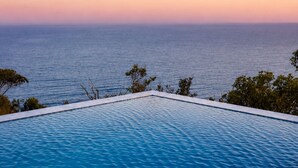 An infinity pool with a view of the ocean at sunset. - All The Views - Ocean & Bush with Heated Infinity Lap and Play Pool (Otford)