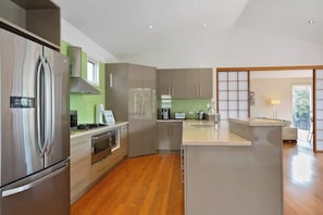 A modern kitchen with stainless steel appliances, a central island, and a view into the living area. - Bella Casa Sorrento (Sorrento)