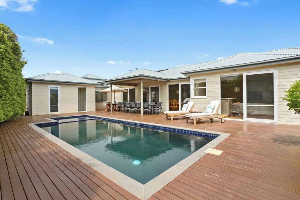 A residential property with a swimming pool, outdoor furniture, and a covered patio area.