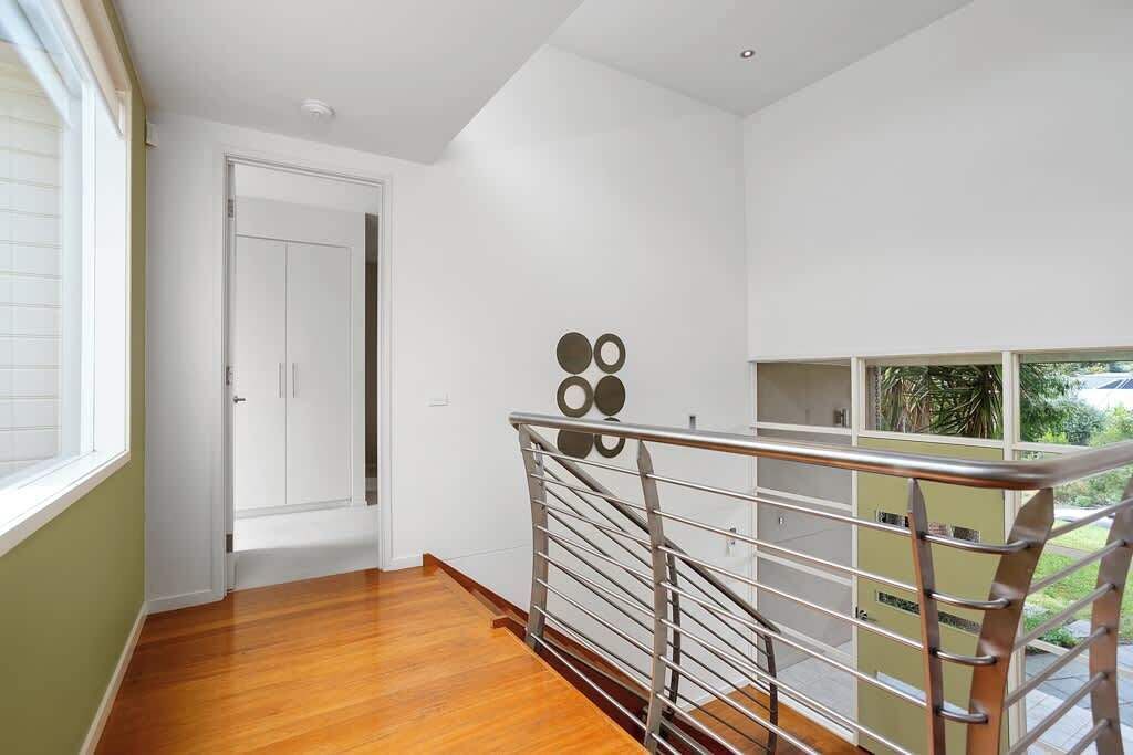 A modern interior with a wooden floor, a metal railing, and a white door.
