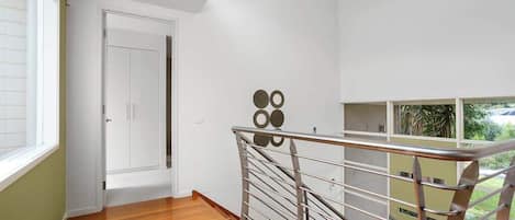 A modern interior with a wooden floor, a metal railing, and a white door.