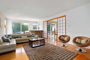 A modern living room with a sofa, coffee table, and wicker chairs.