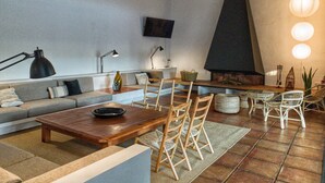 A modern living room with a sofa, coffee table, and chairs. There is a fireplace, a television mounted on the wall, and a dining table with chairs. - An architectural gem in Las Tablas de Daimiel (Daimiel)