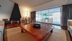 A spacious living room with a wooden dining table, several chairs, a fireplace, and large windows offering a view of the outdoors. - An architectural gem in Las Tablas de Daimiel (Daimiel)