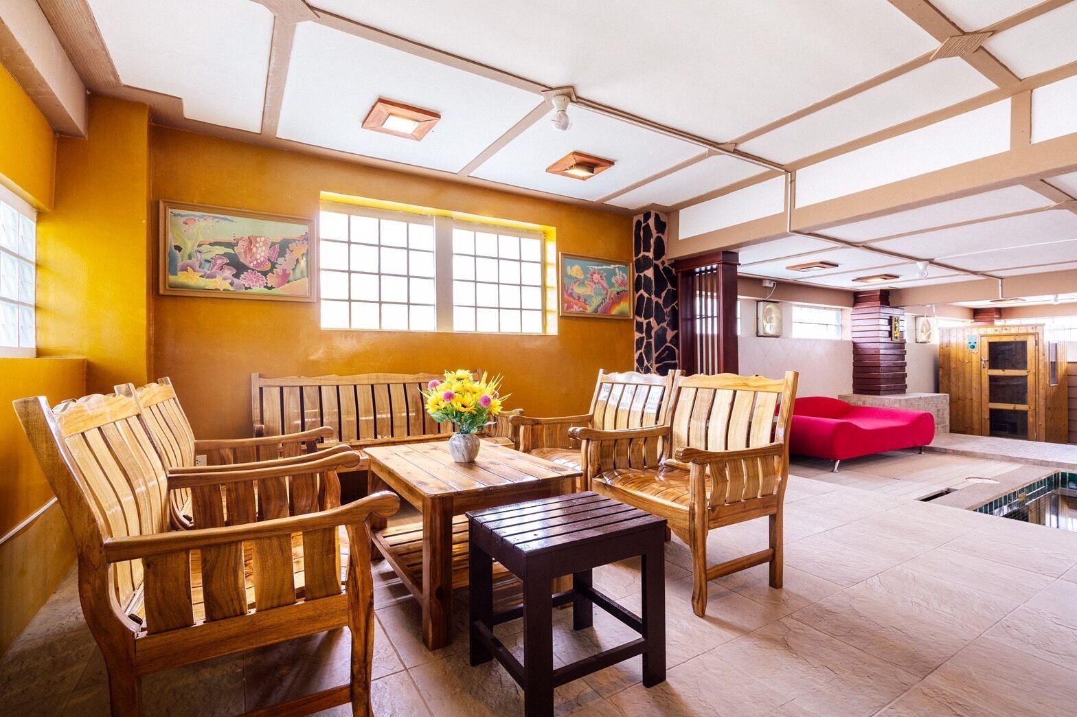 A room with wooden furniture, a table, and a vase of flowers.