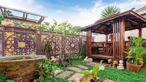 A garden with a wooden pergola, a decorative fence, and various potted plants. - Anyaburi Private Pool Villa (Chalong)