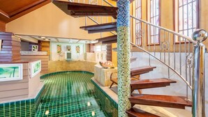A spiral staircase with a mosaic column, a small pool, and a wooden reception desk. - Anyaburi Private Pool Villa (Chalong)