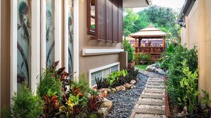 A narrow pathway leading to a gazebo surrounded by lush greenery and a variety of plants. - Anyaburi Private Pool Villa (Chalong)