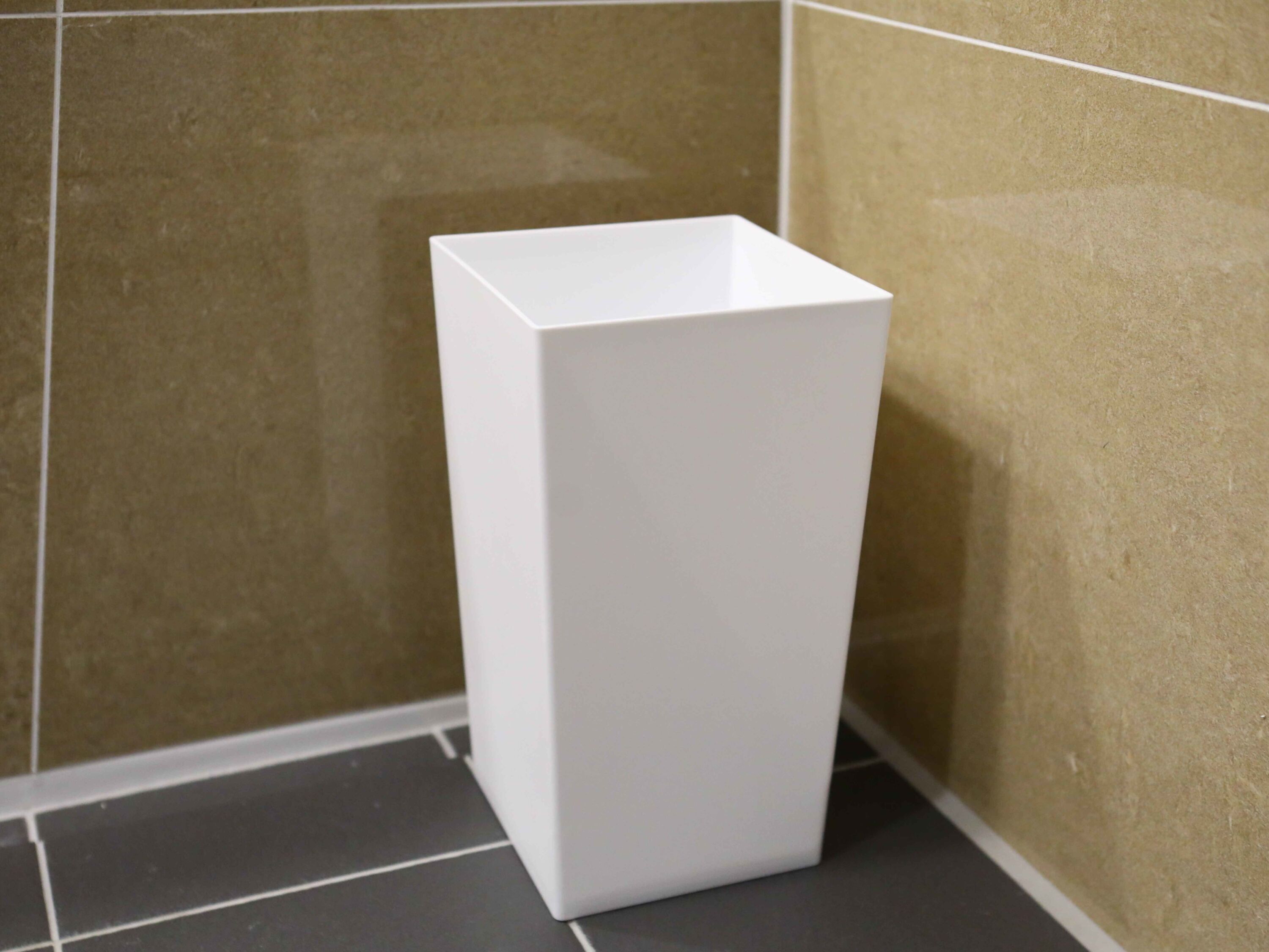 A white, rectangular, empty bathroom sink against beige tiled walls.