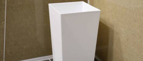 A white, rectangular, empty bathroom sink against beige tiled walls.