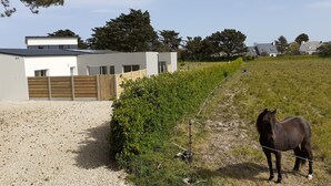 A stable with a horse, a modern building, and a fenced area. - Villa le Nid Des Dunes & Spa-1 Front de Mer (Santec)