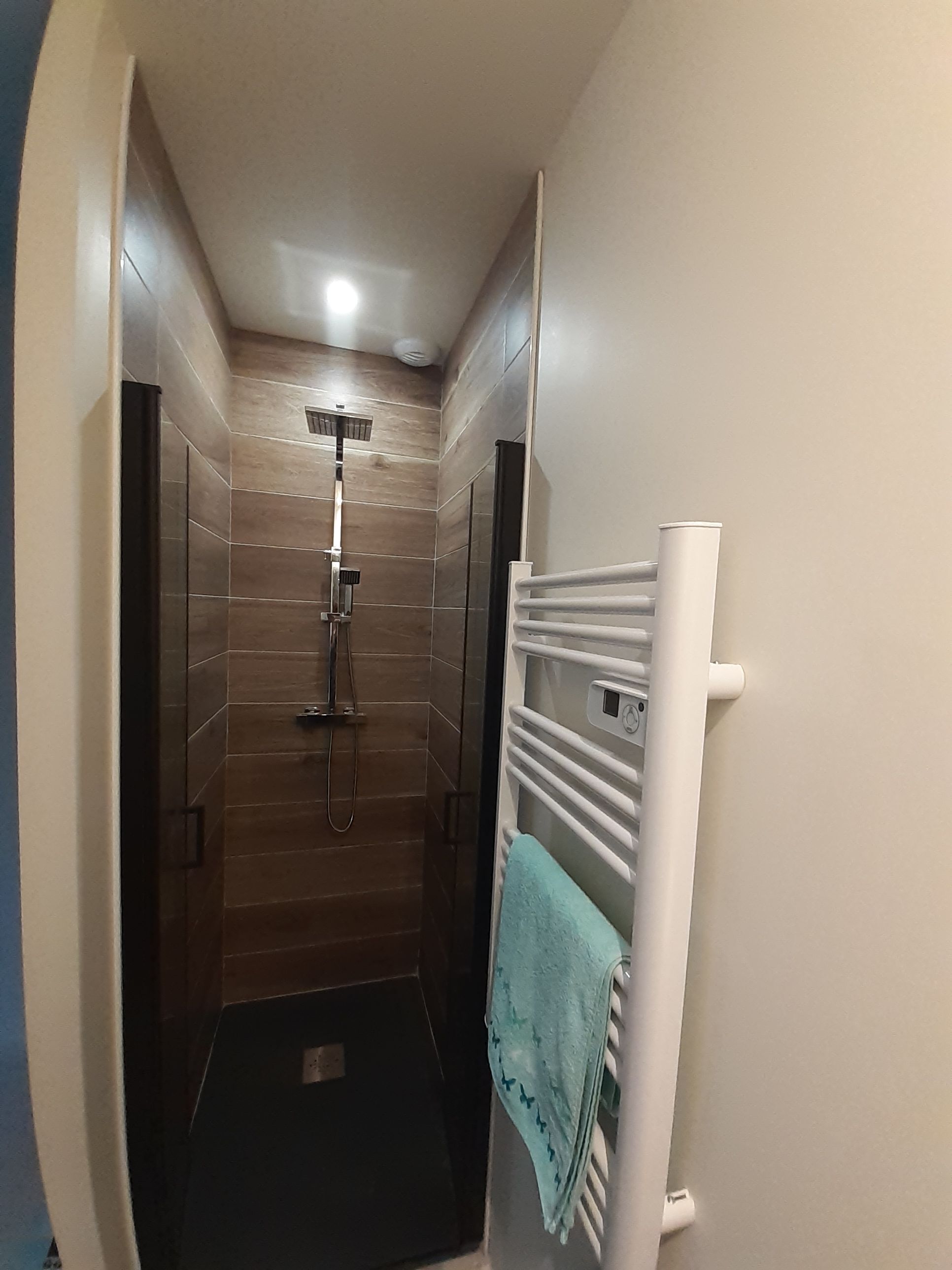 Une salle de bain moderne avec une douche, un porte-serviettes et un sol carrelé.