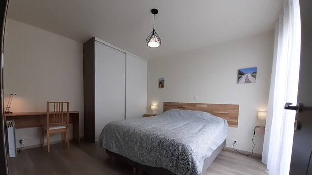 Une chambre à coucher avec un lit, un bureau, une chaise et une armoire.